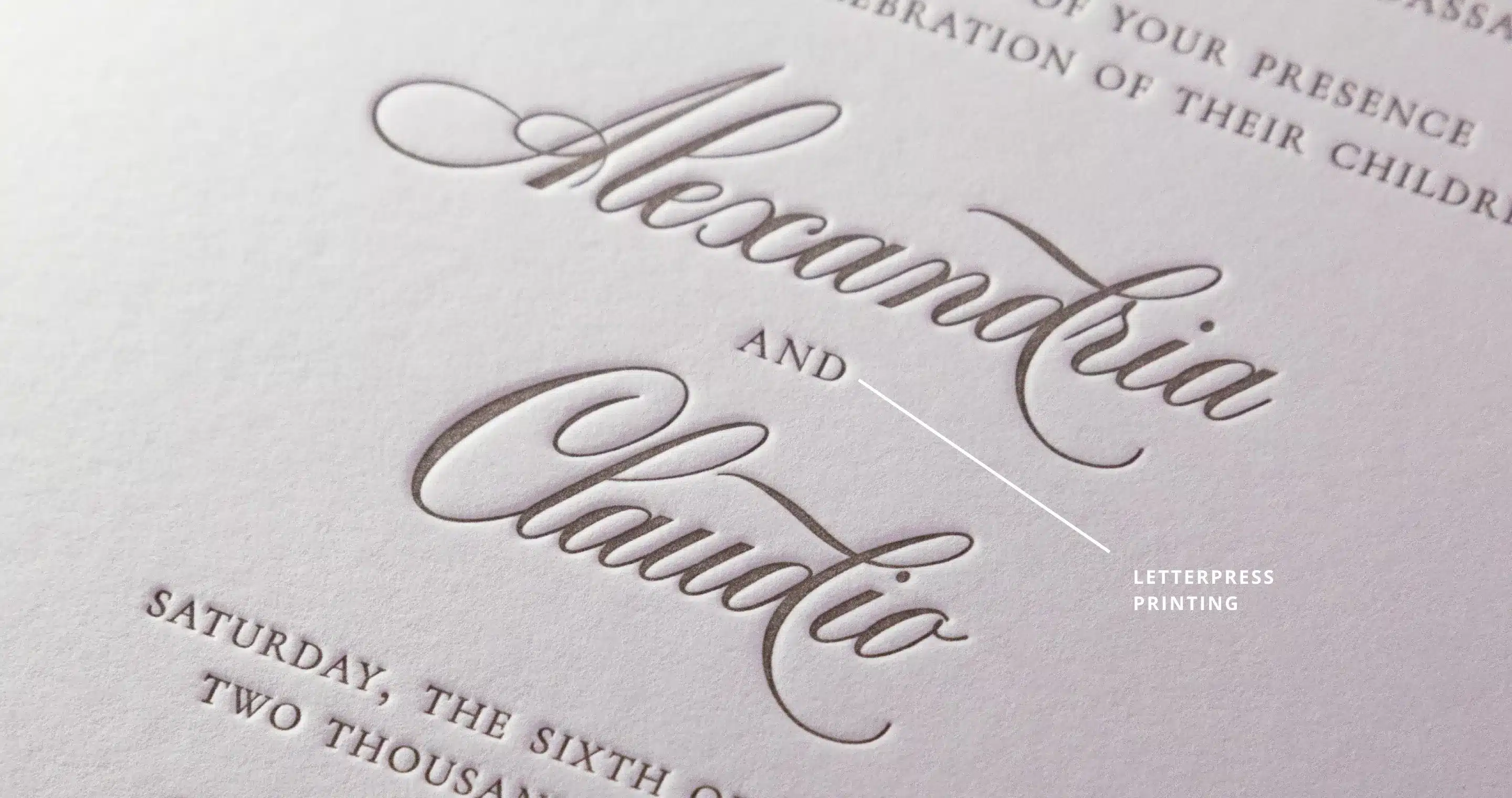 Close-up of a letterpress invitation featuring the names "Alexandria" and "Claudio" in elegant script.