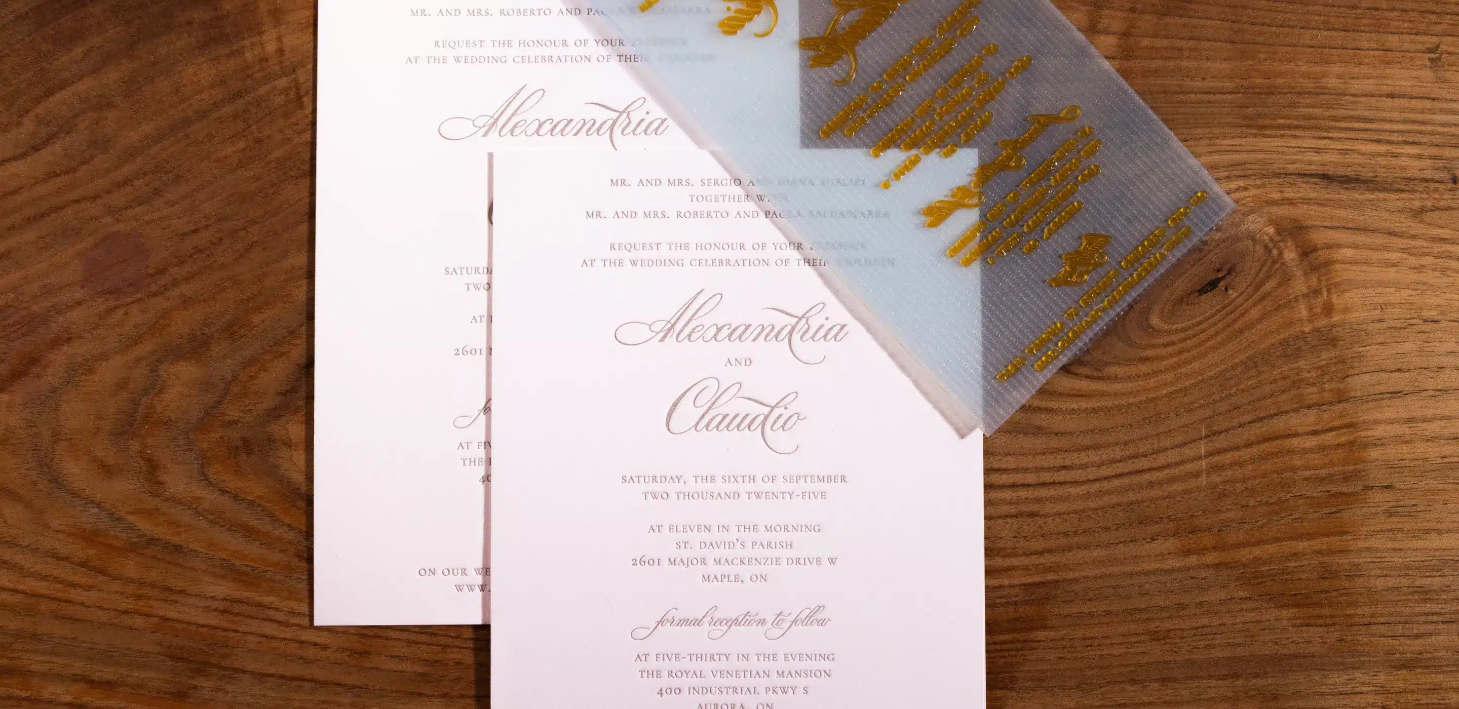 close-up of wedding invitations featuring names "Alexandria" and "Claudio" on a wooden surface.