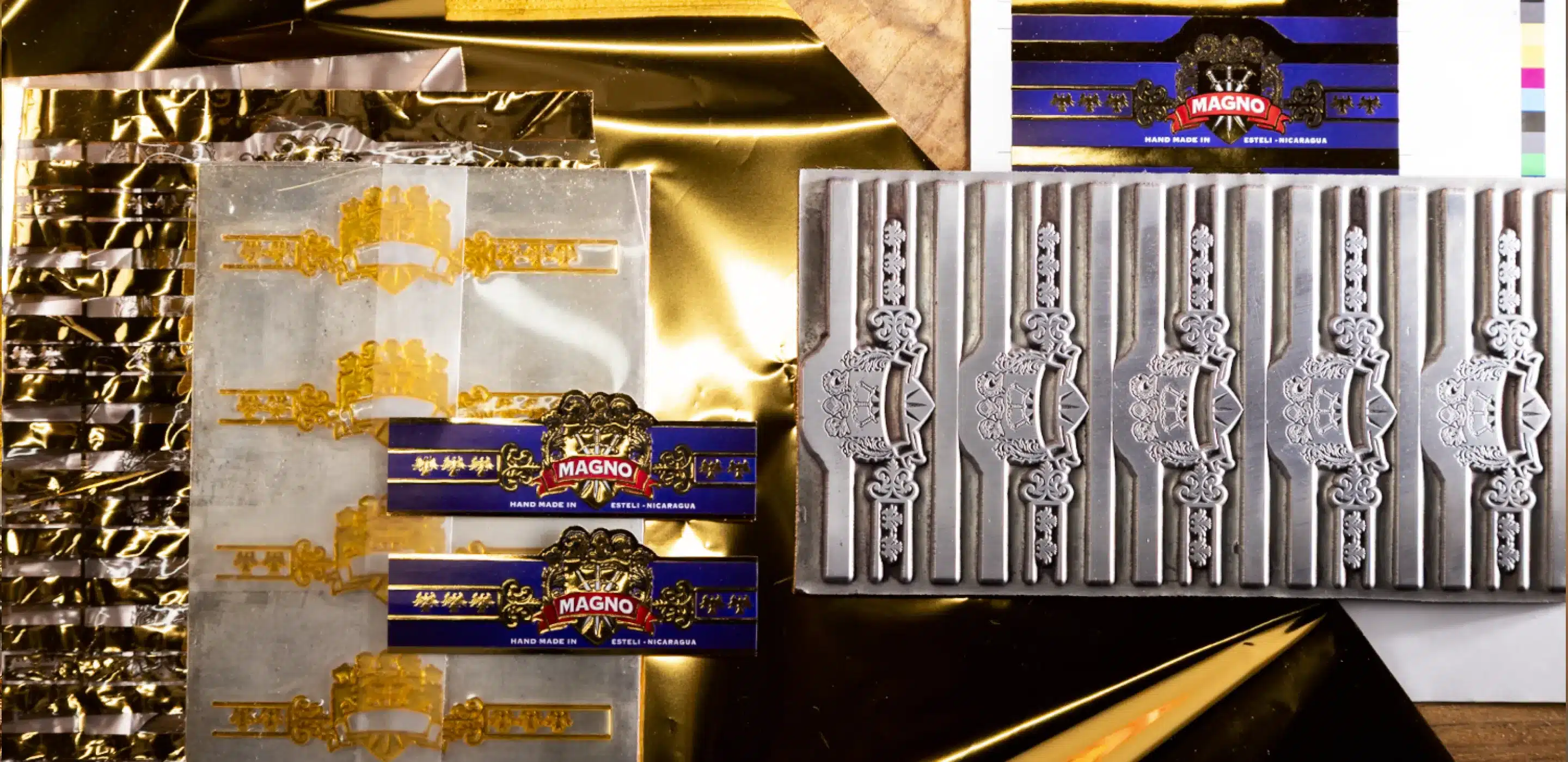collection of gold and silver cigar bands and molds arranged on a shiny gold background.